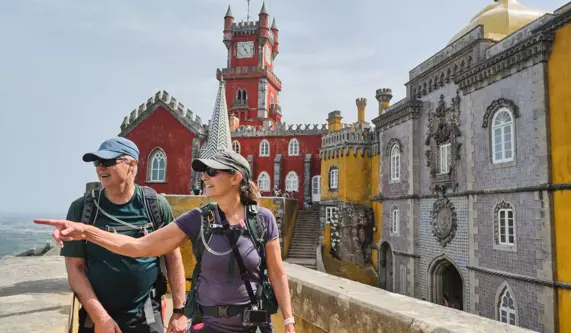 A couple strolls hand in hand along a scenic path leading to a majestic castle in the distance.
